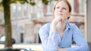 woman sitting with hand under chin, reflecting