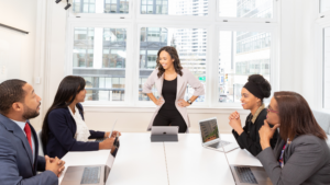 woman standing at head of table talking to other leaders, both black women and a man