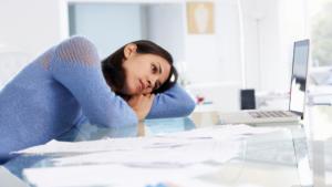 woman leaning on a desk, laying head on her arm