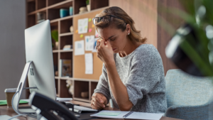 woman looking down with eyes closed and hand pinched in between her eyebrows, looks burnout or tired