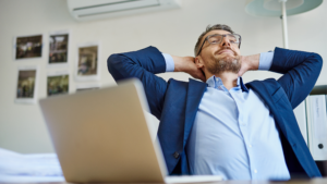 man leaning back with hands behind his head, taking a break