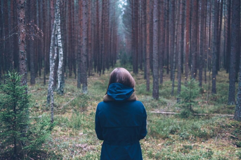 girl standing in forest alone