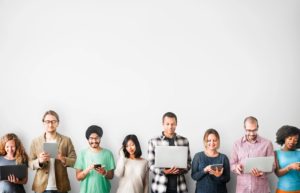 8 people standing together with their phones and lap tops