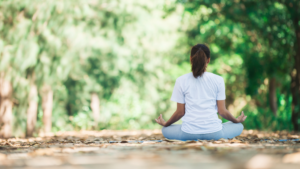 woman sitting on the ground meditating with hands on her lap