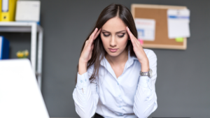 Woman leader with hands on either side of her head, looking down, thinking of 4 pitfalls to avoid in leadership