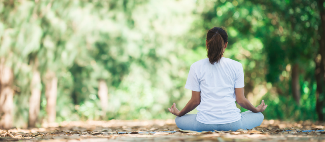 woman sitting on the ground meditating with hands on her lap