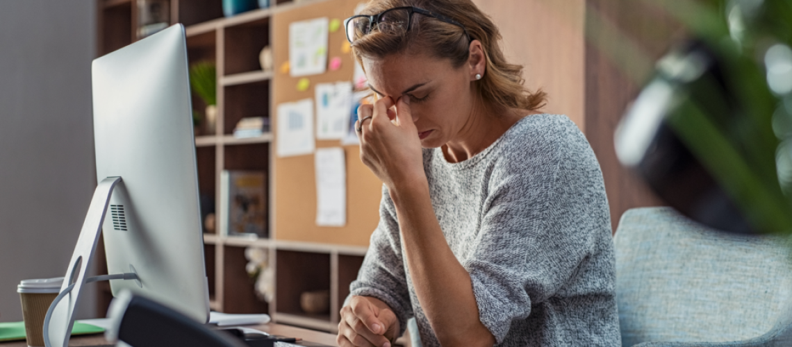 woman looking down with eyes closed and hand pinched in between her eyebrows, looks burnout or tired