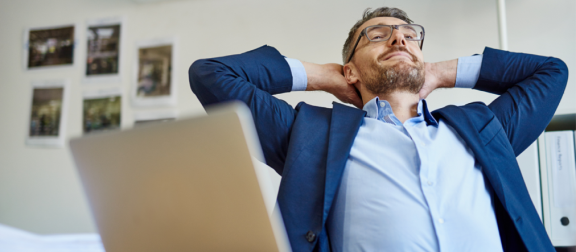 man leaning back with hands behind his head, taking a break