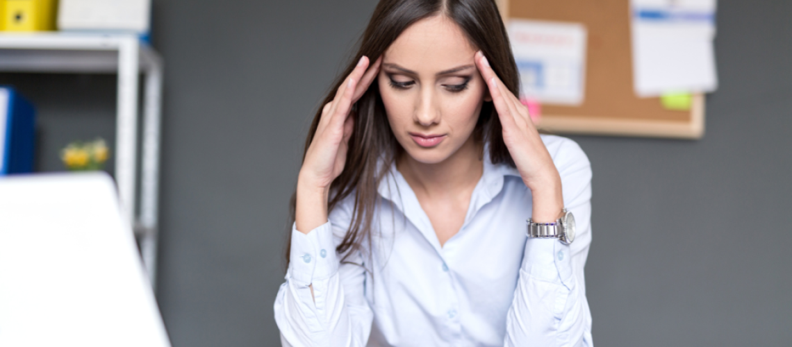 Woman leader with hands on either side of her head, looking down, thinking of 4 pitfalls to avoid in leadership