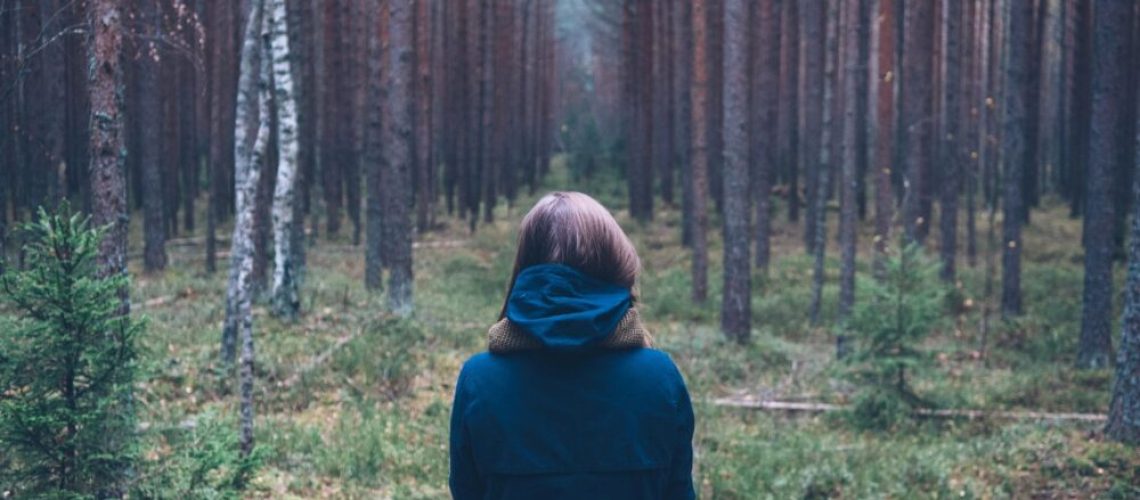 girl standing in forest alone