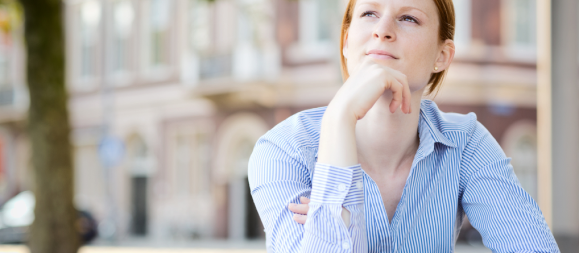 woman sitting with hand under chin, reflecting