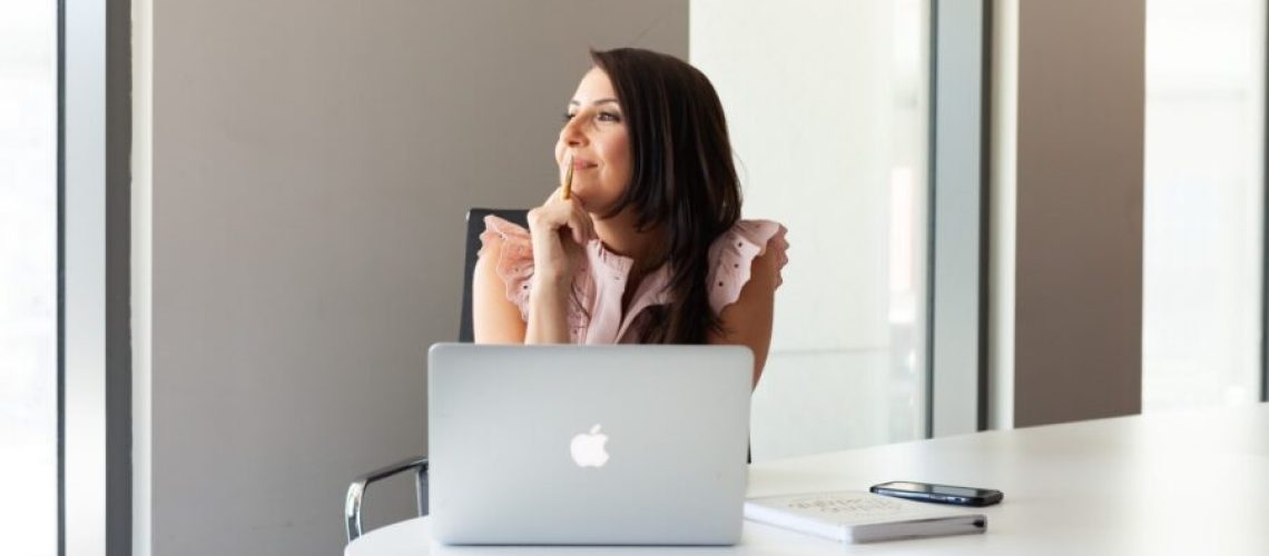 woman looking to her right with hand under her chin, thinking